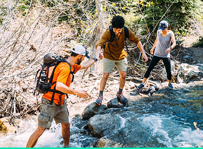 Three people crossing a river