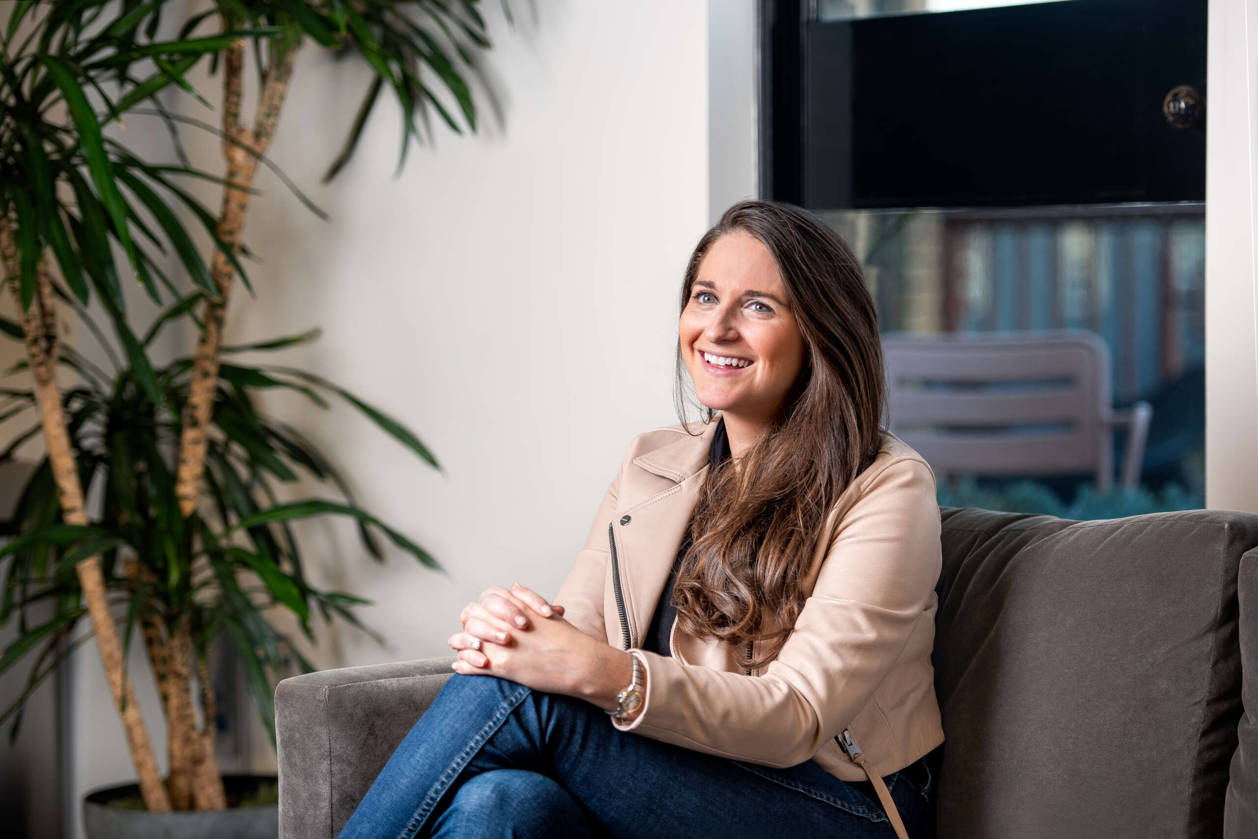 A photo of Liz Wessel, seated on a couch, smiling